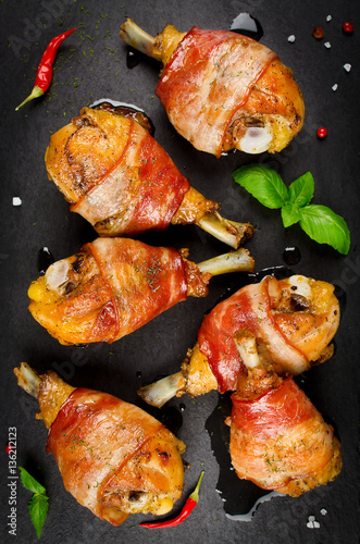 Bacon wrapped chicken legs on a black background