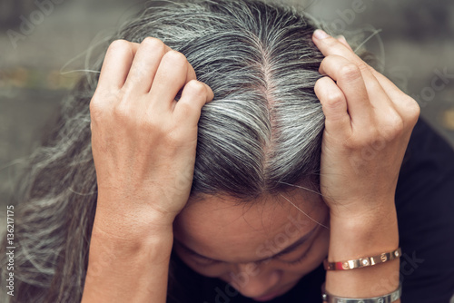 woman and gray hair with worried stressed face looking down photo