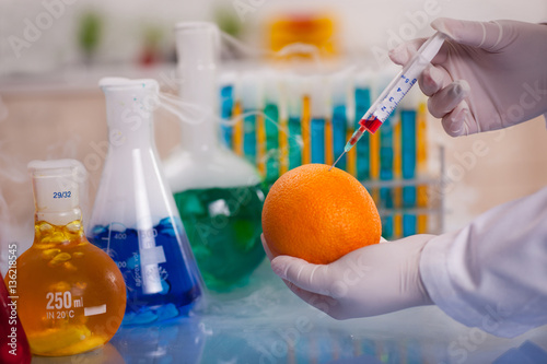 GMO experiment scientist injecting liquid into orange in agricul photo