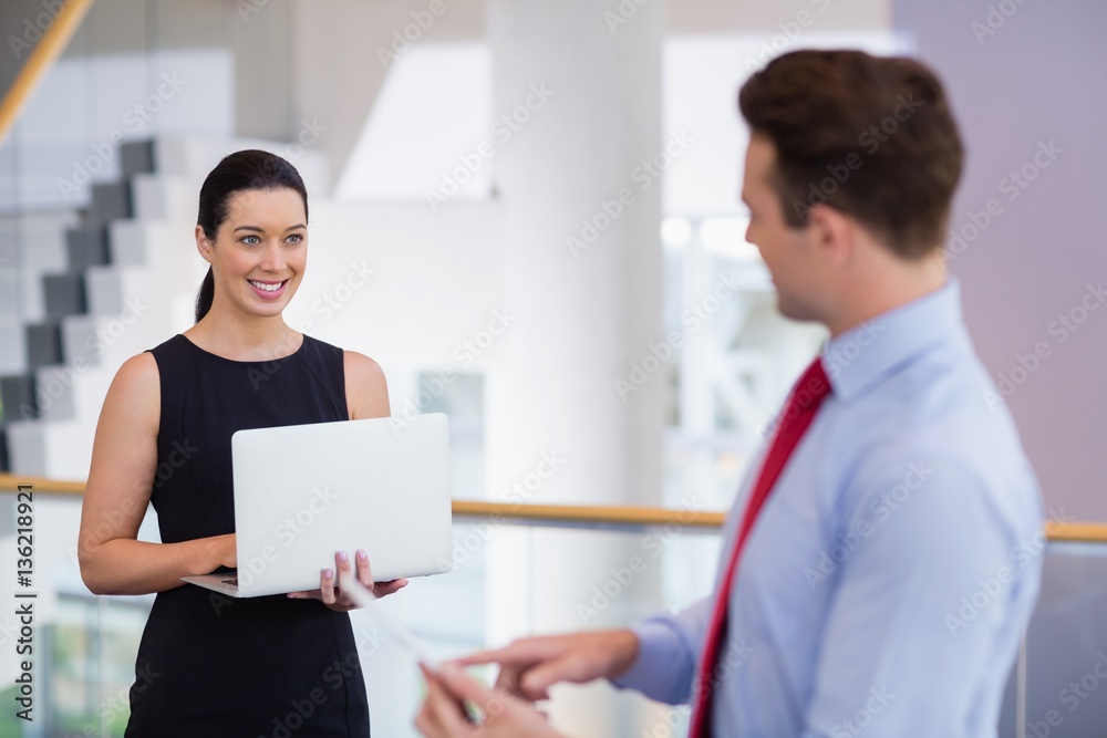 Businesswoman holding laptop and interacting with colleague Businesswoman holding laptop and interacting with colleague