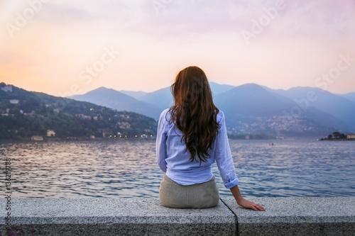 Young woman admiring sunset at the lake Como