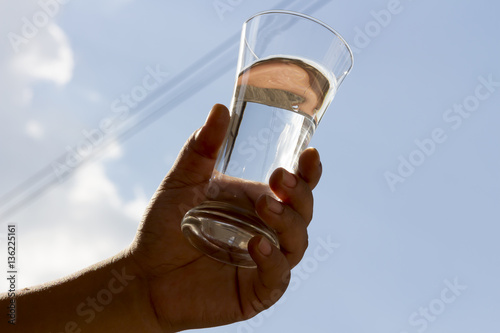 Holding a glass of water on a sky background.