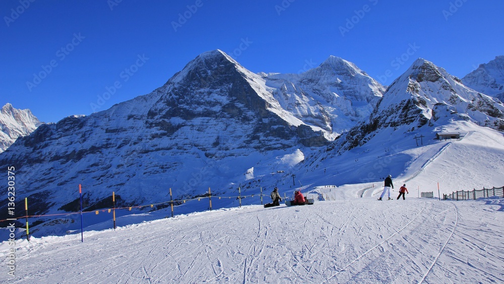 Ski slope and snow covered mountains Eiger, Monch and Lauberhorn. Winter day in Grindelwald, Swiss Alps.
