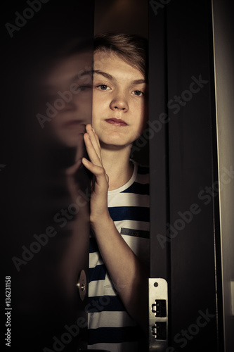 Teenager boy behind ajar door