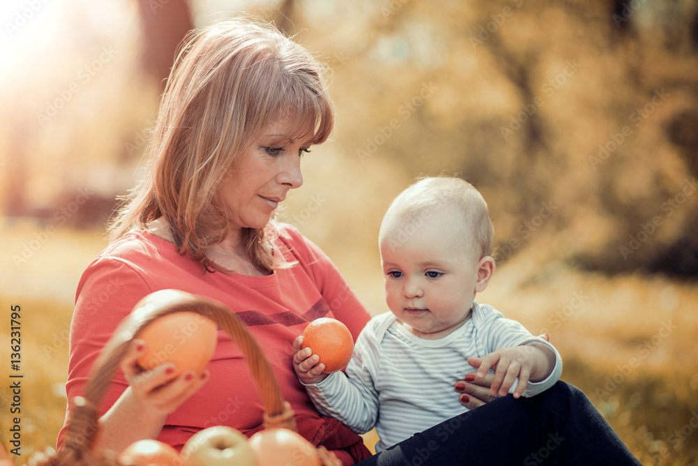 Happy mother and baby sitting on grass in park