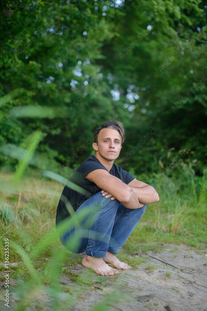 cute sexy sporty guy sitting barefoot on the river Bank Stock Photo | Adobe  Stock