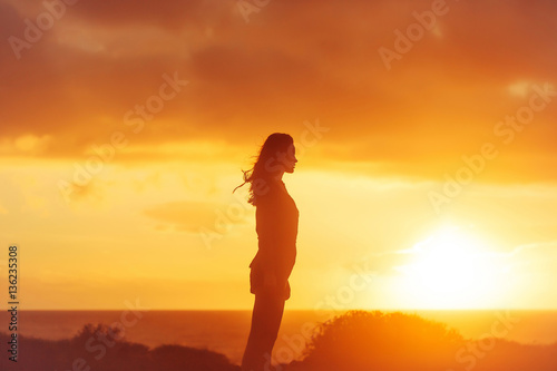 Black silhouette of pretty girl on sea beach at sunset