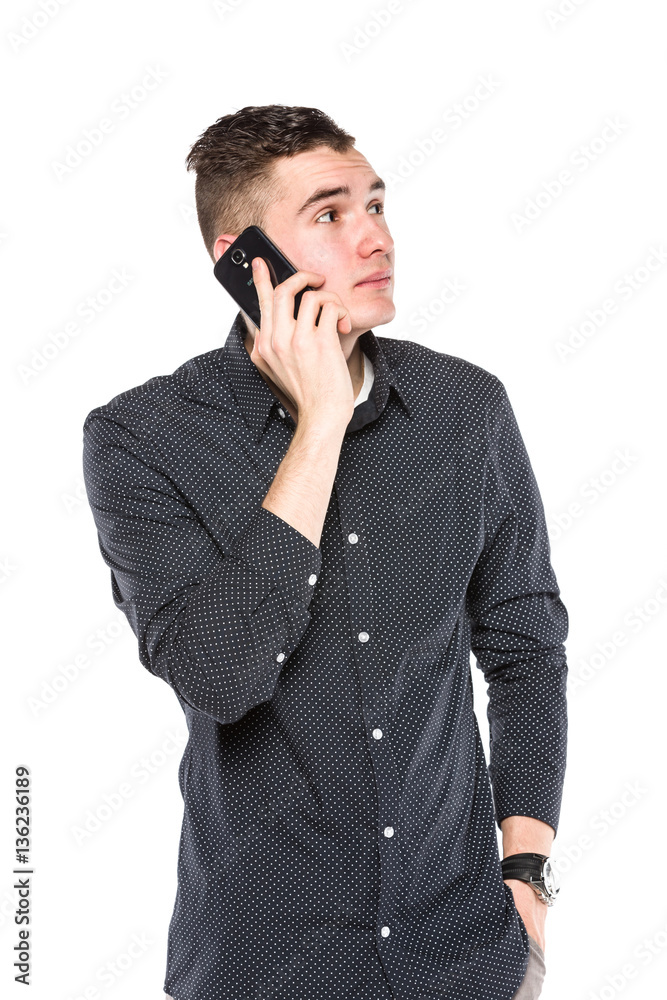 A young man talking cell phone and holding his hand in his pocke A young man talking cell phone and holding his hand in his pocke