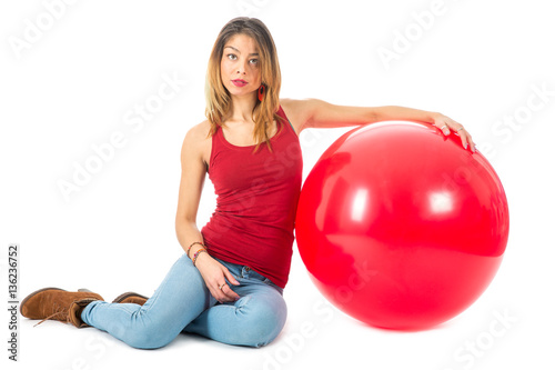 Woman sitting on floor with big red balloon