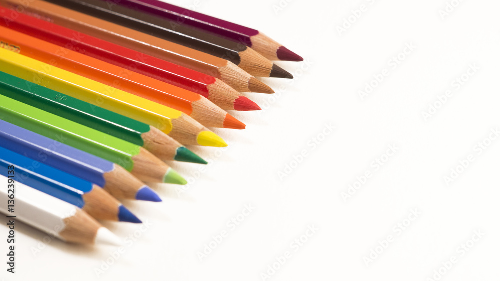 Colored pencils laying neatly in a row pointing downwards to the right on a white background Colored pencils laying neatly in a row pointing downwards to the right on a white background