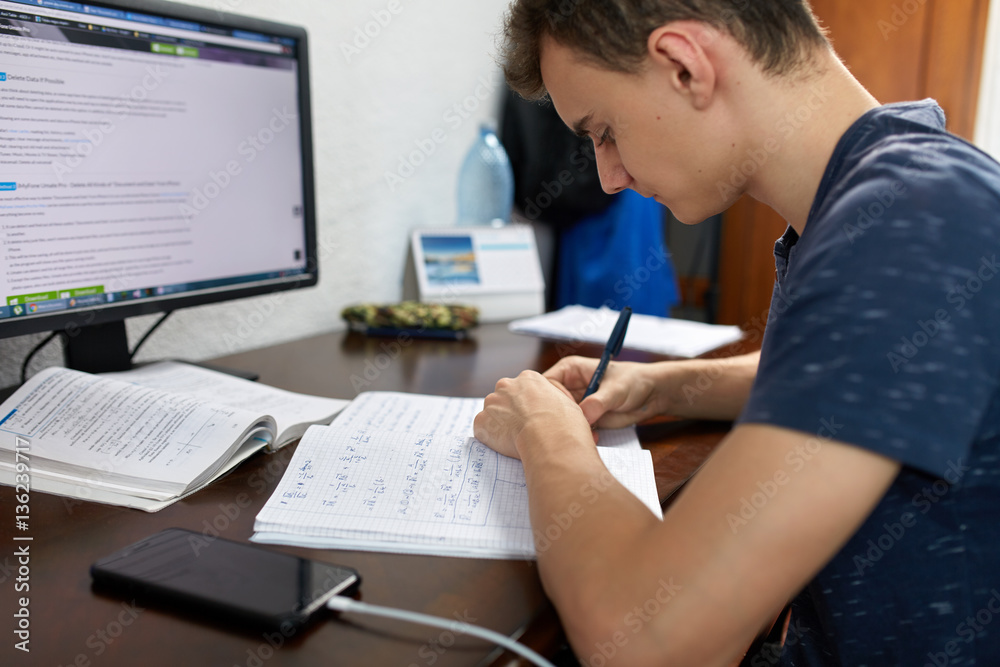 Teenager doing homework with computer Teenager doing homework with computer
