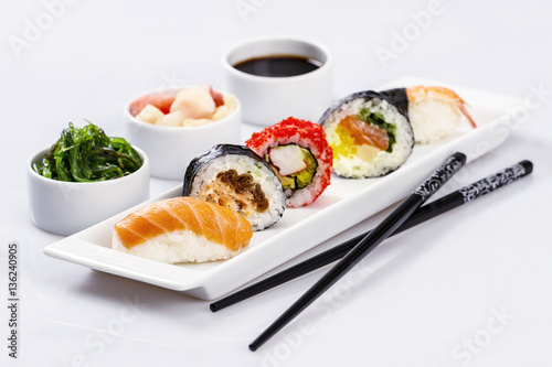 various kinds of sushi on a white plate, chopsticks, wasabi, pic
