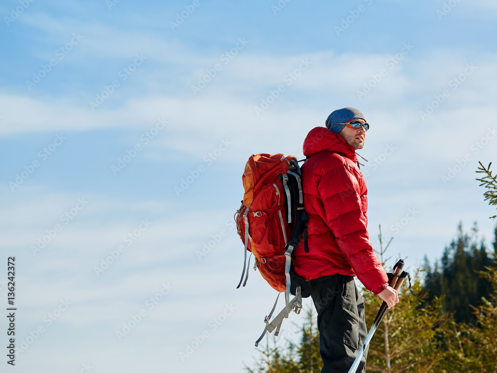 hiker in red down jacket with backpack near the tent in the Carpathians mountains at winter