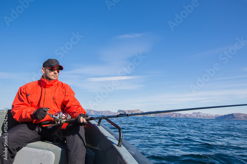 Fisherman athlete wearing sunglasses with a spinning rod in his