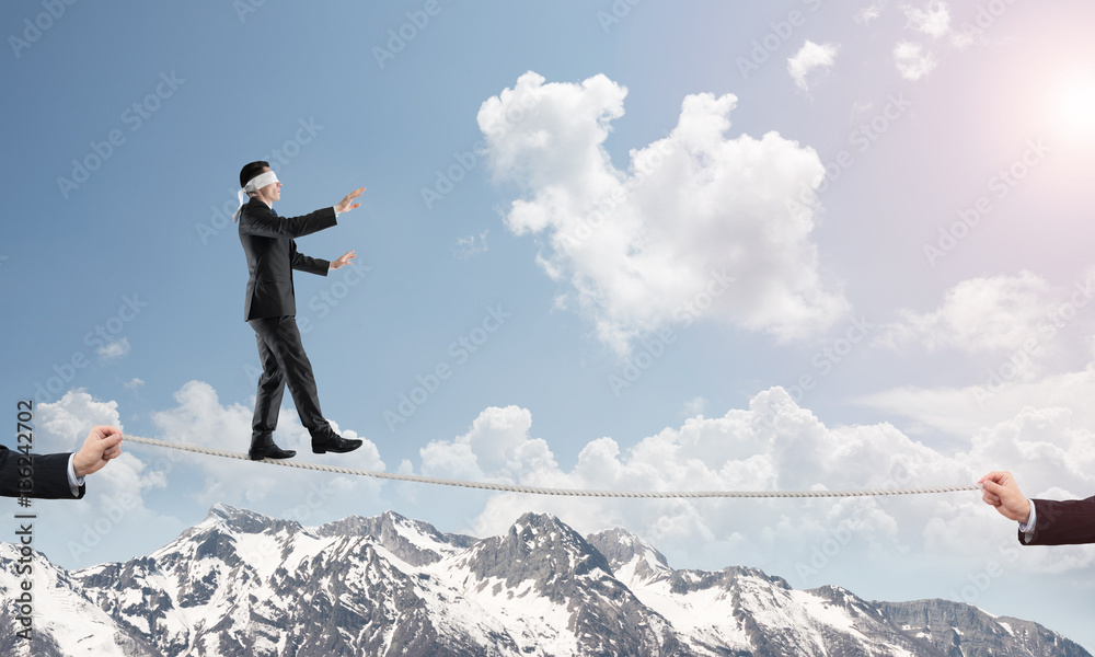 Business concept of risk support and assistance with man balancing on rope Business concept of risk support and assistance with man balancing on rope