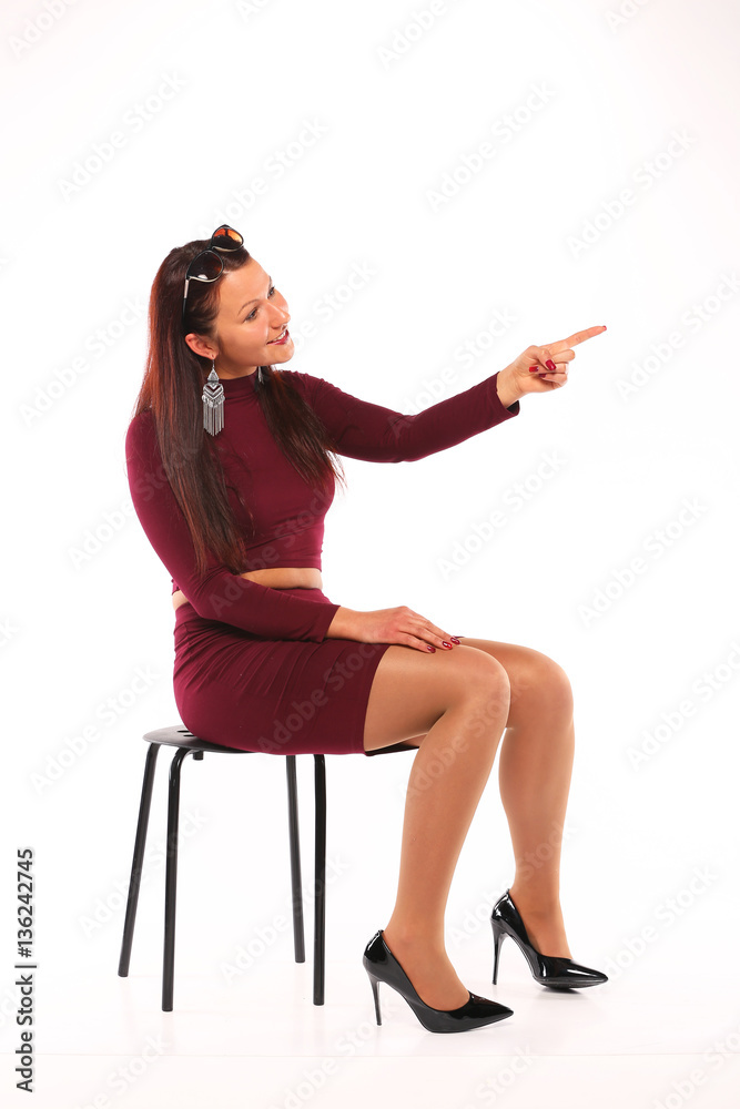 young girl sitting on on the side a chair in burgundy dress with on white background young girl sitting on on the side a chair in burgundy dress with on white background