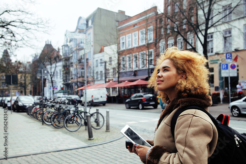 young pretty african american girl with curly hair making photo on a tablet, lifestyle people concept, tourist in european german city