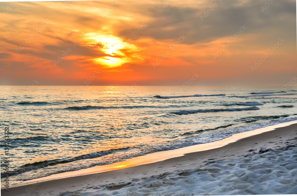 Fototapeta premium Beautiful orange sunset with wispy clouds. Tourist travel destination location. Beach shoreline setting for background or backdrop.