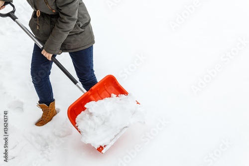 Woman with shovel cleaning snow. Winter shoveling. Removing snow after blizzard.
