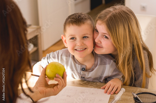 Cute little brother and sister getting apple from doctor. photo