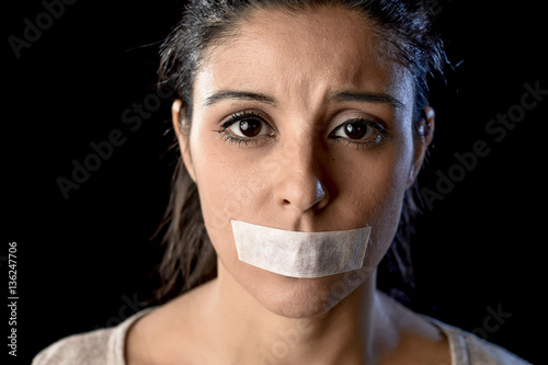 close up portrait of young attractive woman with mouth and lips sealed in adhesive tape restrained photo