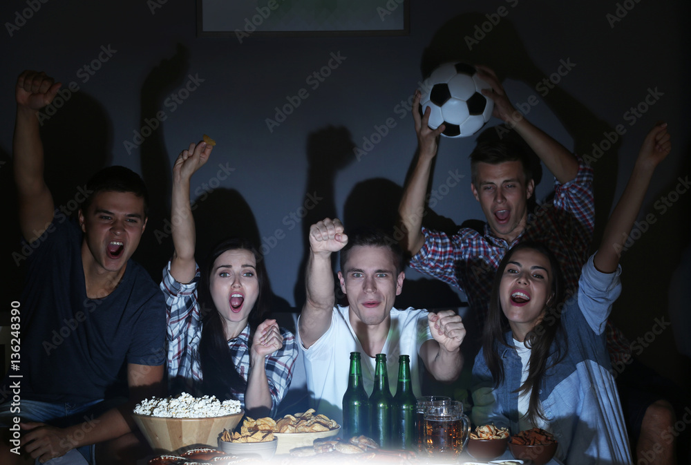 Young fans watching football match on TV late in evening with beer and snacks - obrazy, fototapety, plakaty 