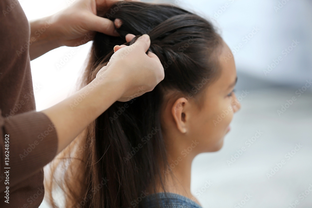 Naklejka premium Woman doing hair of her daughter at home, closeup