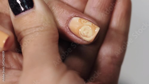 Female beautitian hand draw curls on beige nail in beauty shop, close up white table photo