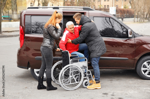 Young couple helping handicapped man to sit in wheelchair © Africa Studio