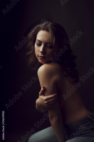 Romantic young woman with lush curly hair at studio