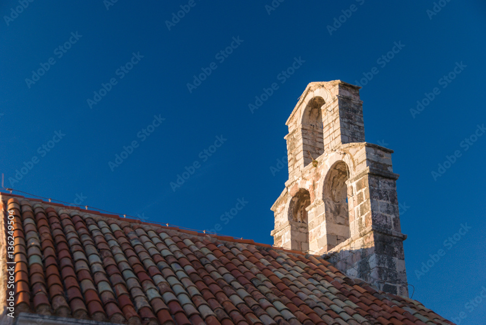 Ancient orthodox church bell tower in Budva old town with deep blue sky in the background
