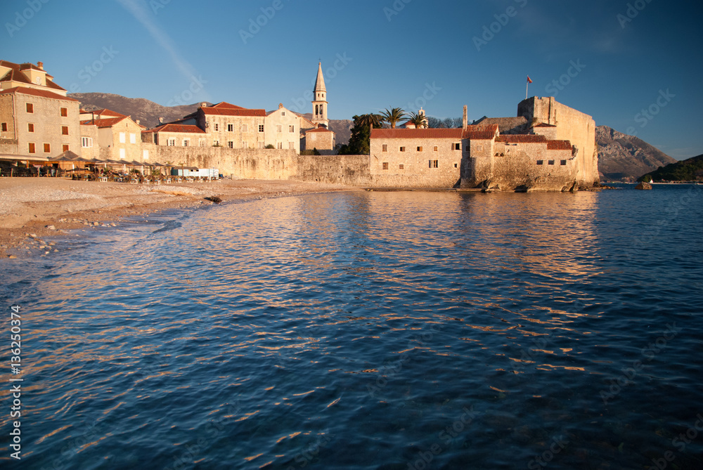 Ancient stone buildings by the sea at sunset in old town Budva, Montenegro