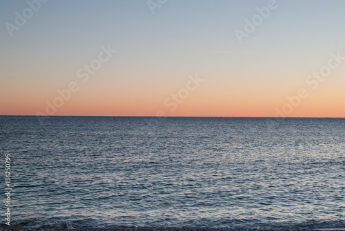 Open sea at sunset with colorful gradient sky background  horizon line splitting the photo in half