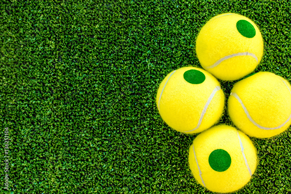 Naklejka premium tennis ball on green background top view mock up