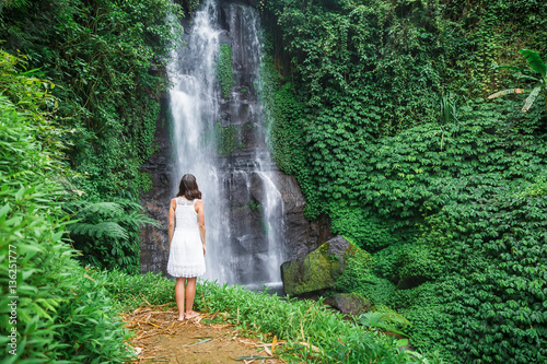 Beautiful asian girl in white dress. Waterfall in tropical jungle on Bali