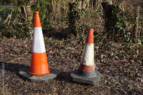 Traffic cones abandoned on waste land near woods