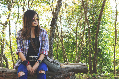 young hipster woman sitting in the park. relax woman expression with film colors tone. soft-focus in the background and over light photo