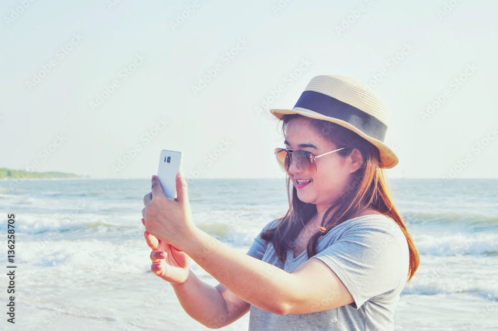Yong woman traveler relaxing and  taking vacation selfie photograph at the beach. Technical Writing light synthesizer