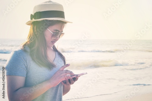 Yong woman traveler relaxing and use mobile phone on a perfect beach