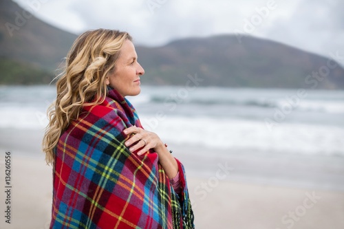 Mature woman wrapped in shawl on the beach