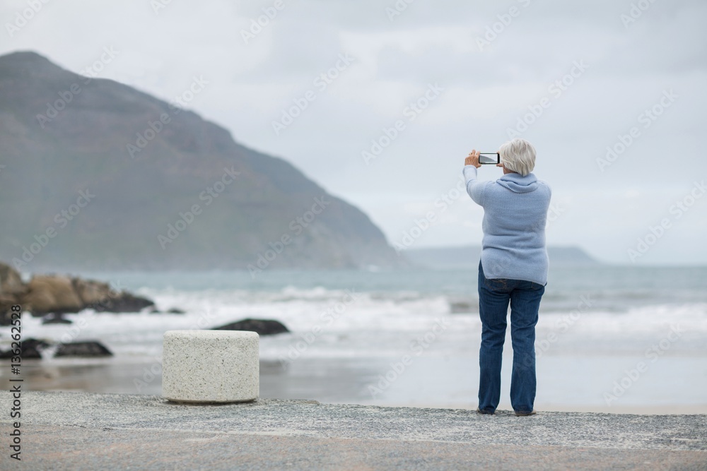 Senior woman photographing scenery using cell phone on the beach Senior woman photographing scenery using cell phone on the beach