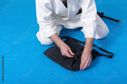 A martial arts master with black belt folding his hakama for Aikido training