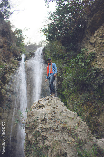 Traveler standing on a rock near waterfall