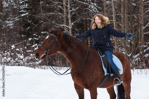 Girl teenager and big horse in a winter
