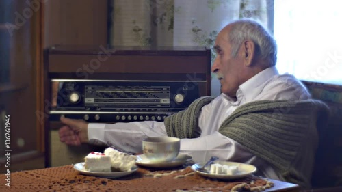 Grandad Setting Radiogram in Lunch Time Tea Cup Cake Piece on the Table in Cosy Living Room Cold Wintry Day at Home Vintage Interior Comfortable Armchair