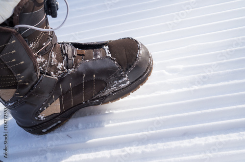 Leg in a brown boot stepping on track cleared of snow.