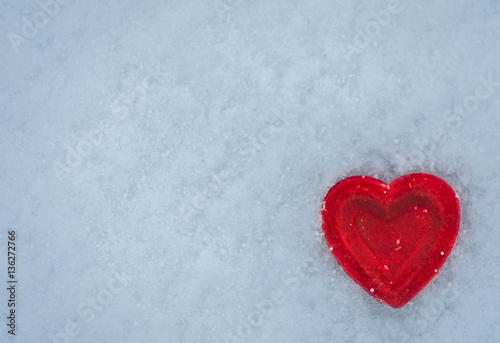 Red heart on a background of snow.