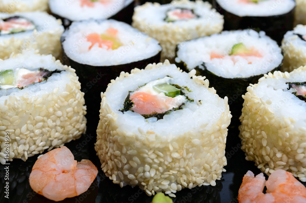 Traditional eastern dish with salmon sushi rolls on a black plate. Traditional eastern dish with salmon sushi rolls on a black plate.