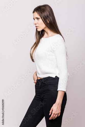 Stylish beautiful young woman model in clothes stands on white background