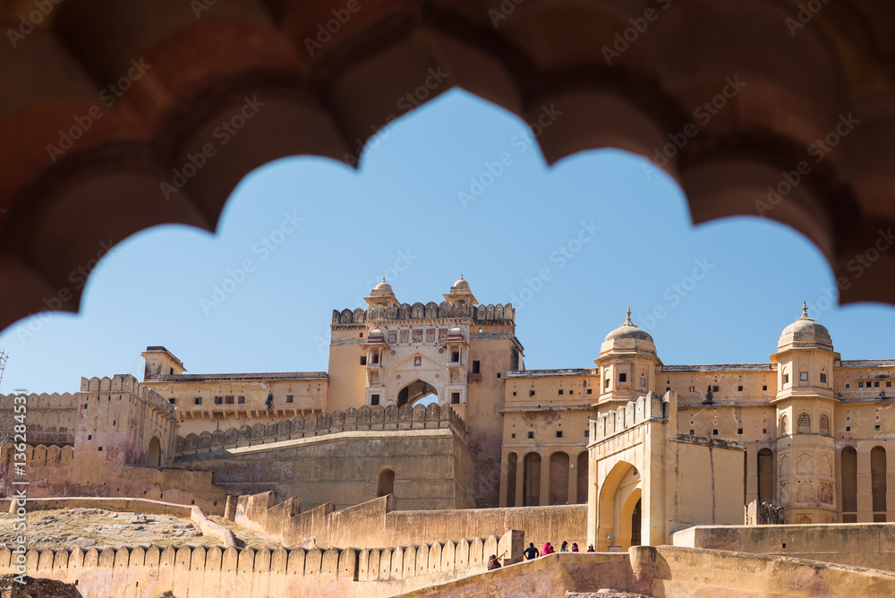 Framed view of the honey toned impressive Amber Fort, famous tourist attraction at Jaipur, Rajasthan, India. Daylight, clear blue sky.